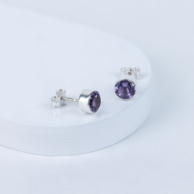 Pair of silver earrings with purple gemstones on a white background