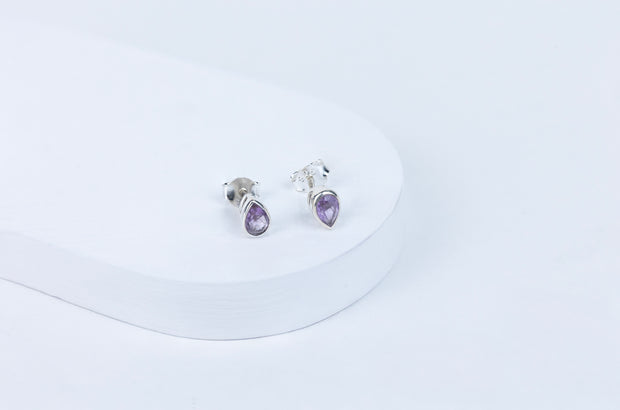 A pair of amethyst oval earrings set in silver mounting, displayed against a white background.