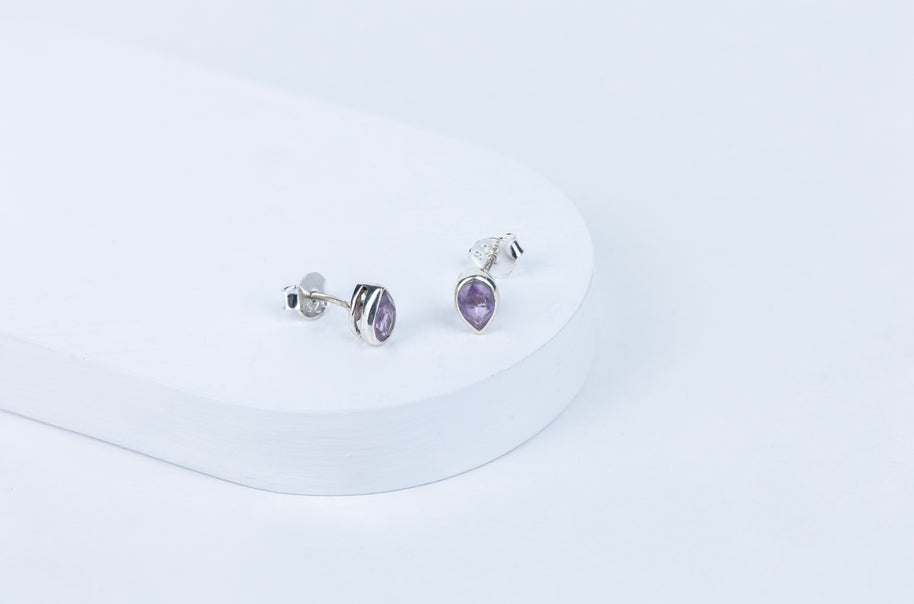 Pair of silver earrings with purple gemstones on a white background