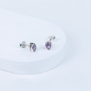 Pair of silver earrings with purple gemstones on a white background
