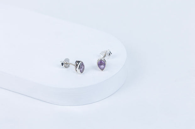Pair of silver earrings with purple gemstones on a white background