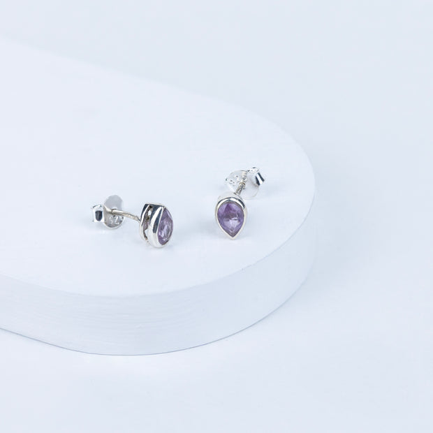 Pair of silver earrings with purple gemstones on a white background