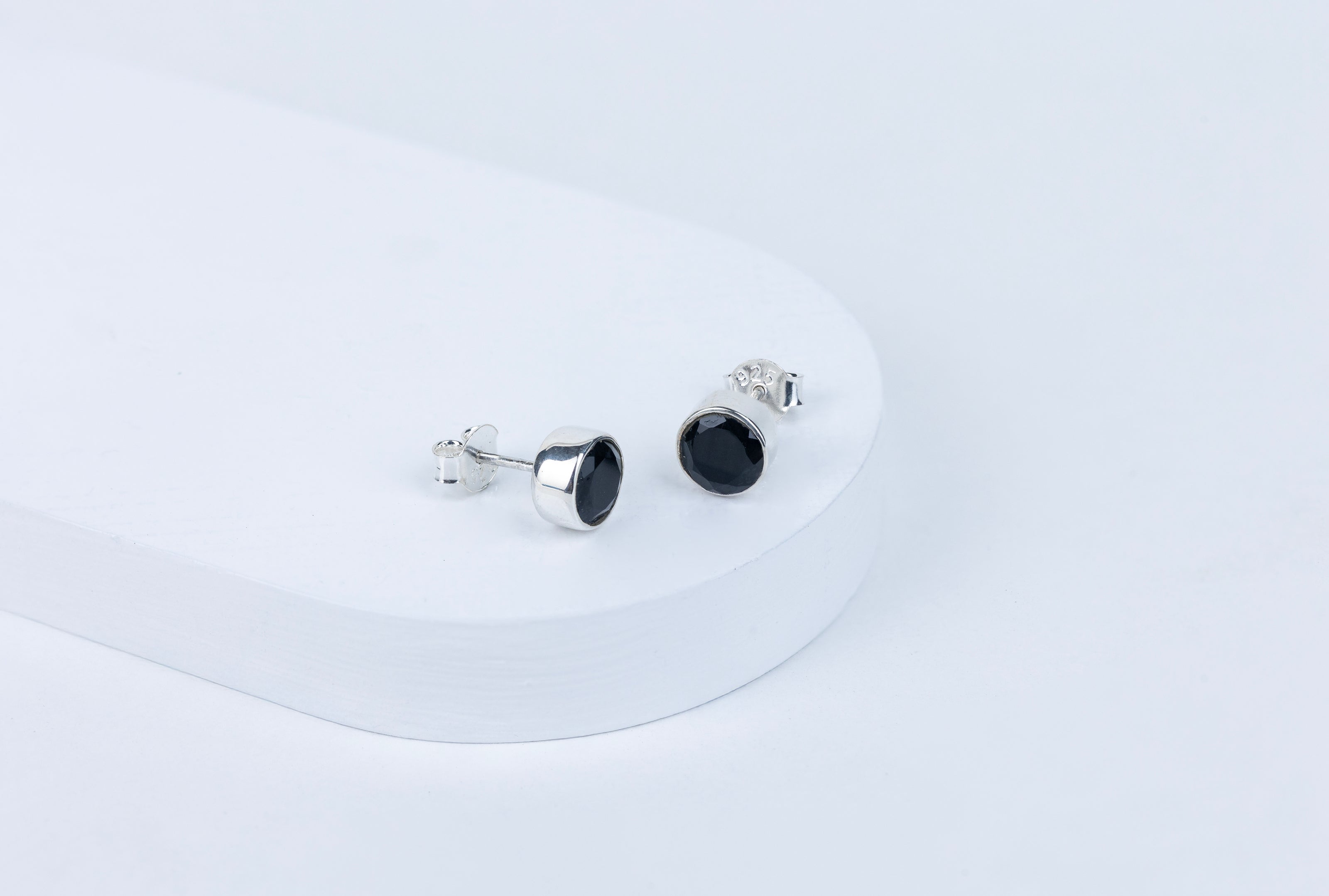 Pair of black stud earrings on a white background