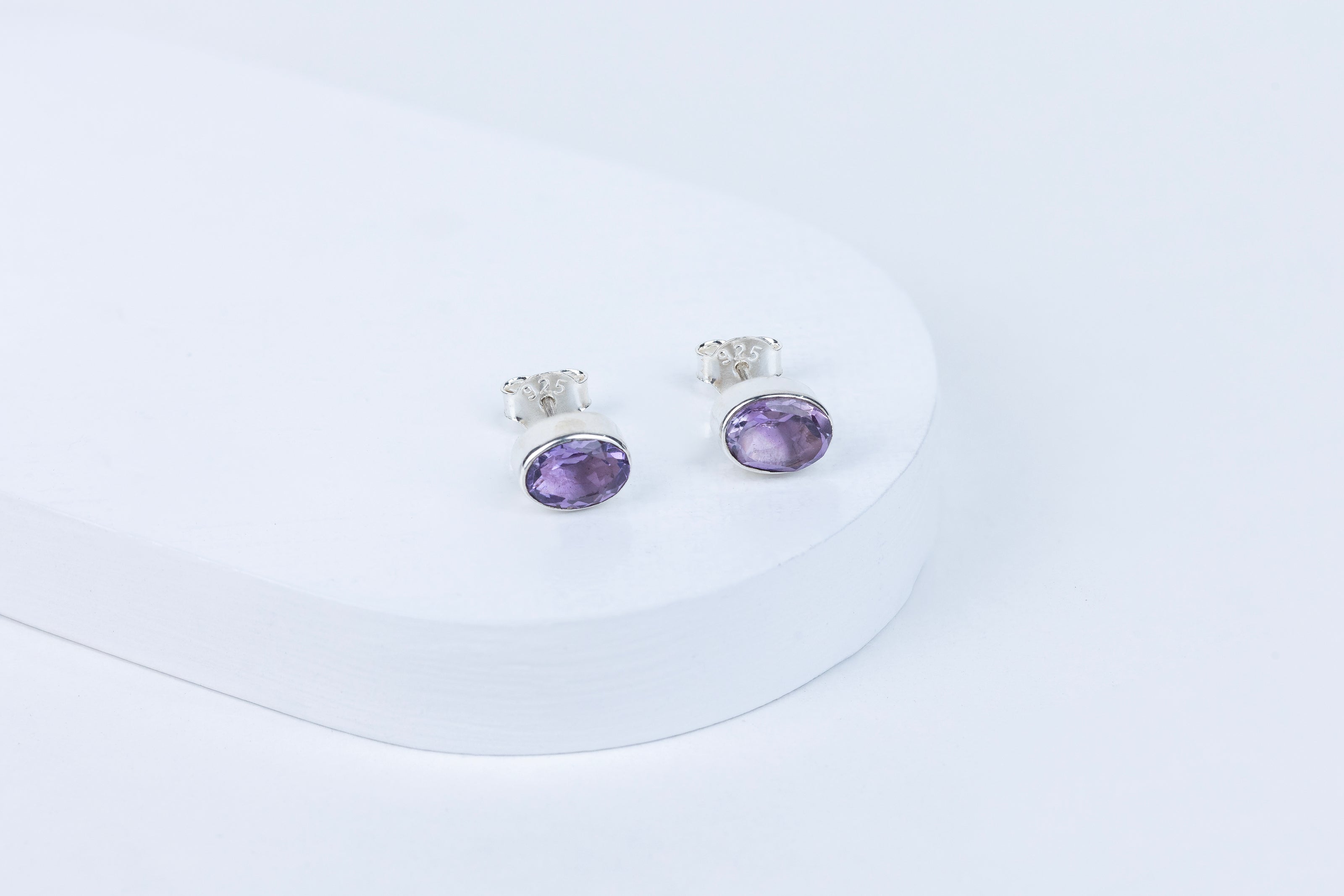 Pair of purple gemstone earrings on a white background