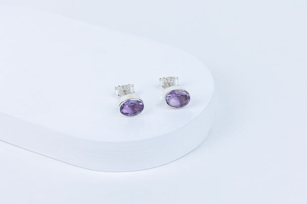 Pair of purple gemstone earrings on a white background