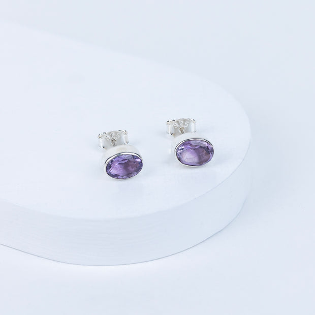 Pair of purple gemstone earrings on a white background