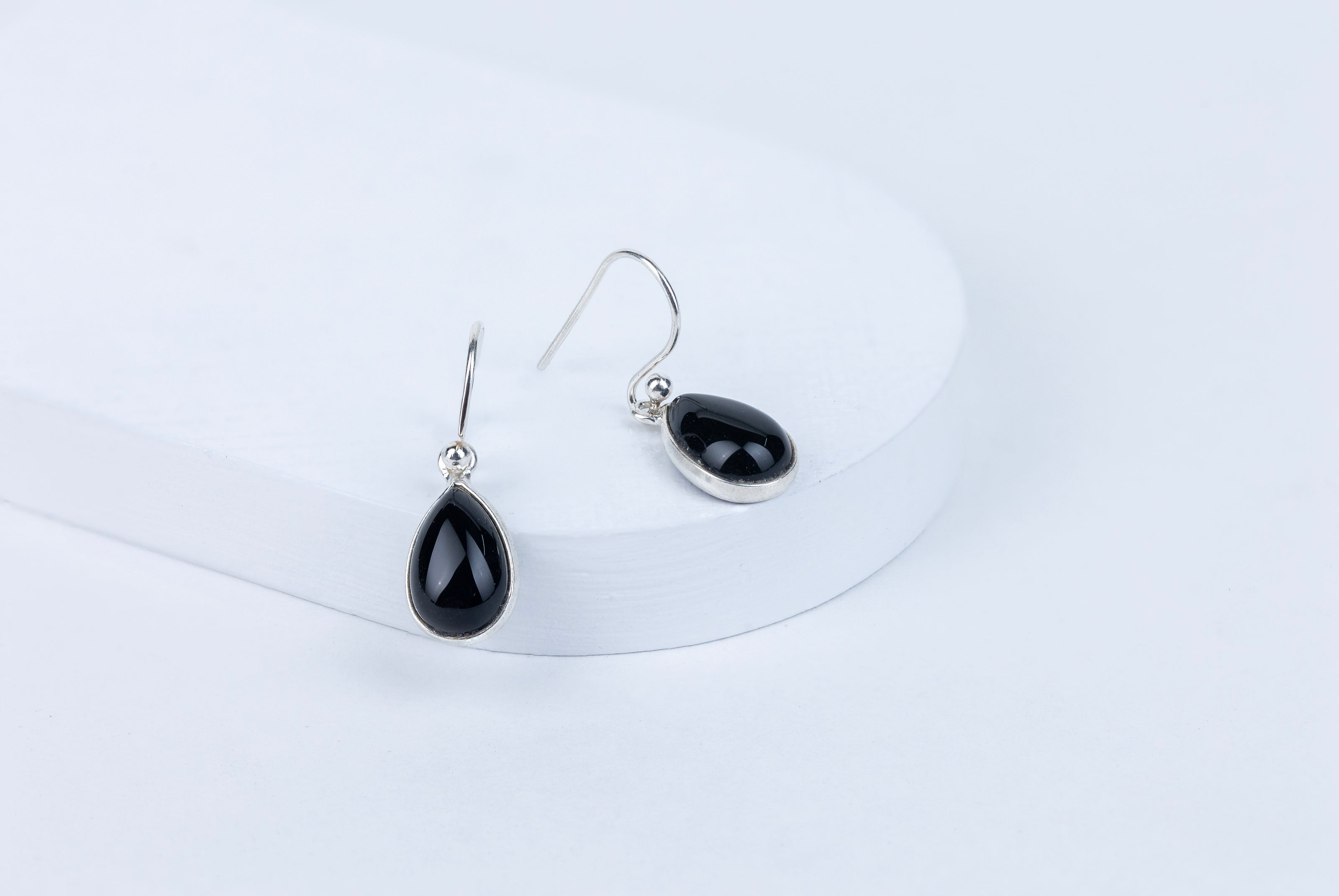 Black teardrop earrings on a white background