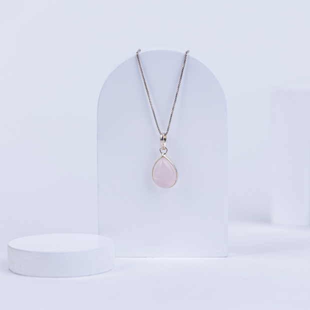 Necklace with a pink rose quartz pendant on a white background