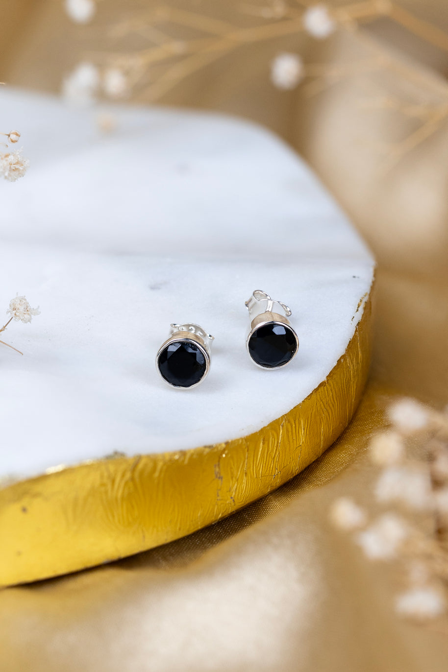 Black stud earrings on a white stone with gold base