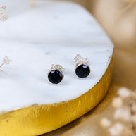 Black stud earrings on a white stone with gold base